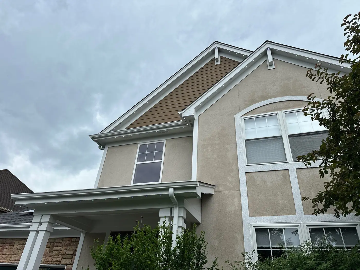 Daytime view of a two-story Chicagoland home with permanent lighting track installed along the fascia and gable, blending into the white trim