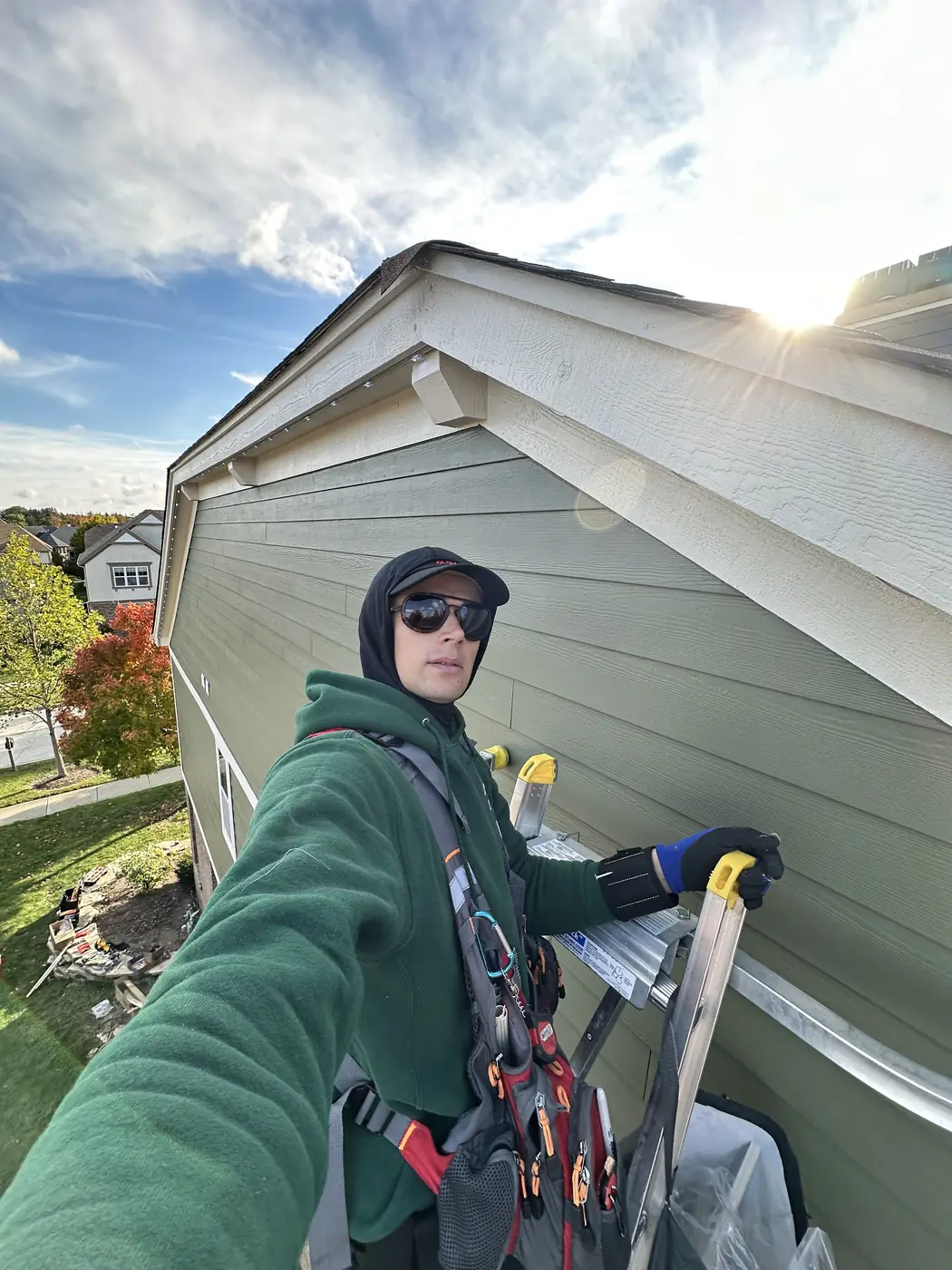 Hanging Lights Club installer on a ladder in daylight during a permanent lighting installation on a Chicagoland home