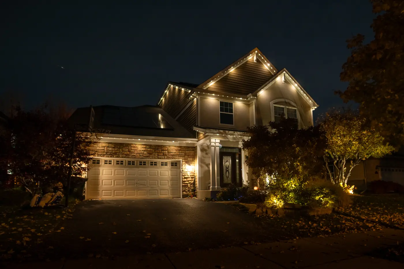 Chicagoland home at night with permanent roofline lighting in warm white and landscape lighting in the foreground